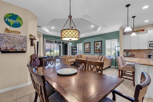 tiled dining area featuring a tray ceiling and a wealth of natural light