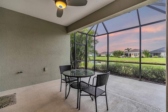 sunroom / solarium featuring ceiling fan and a water view