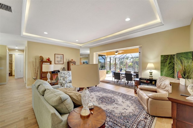 living room with light hardwood / wood-style flooring and a raised ceiling