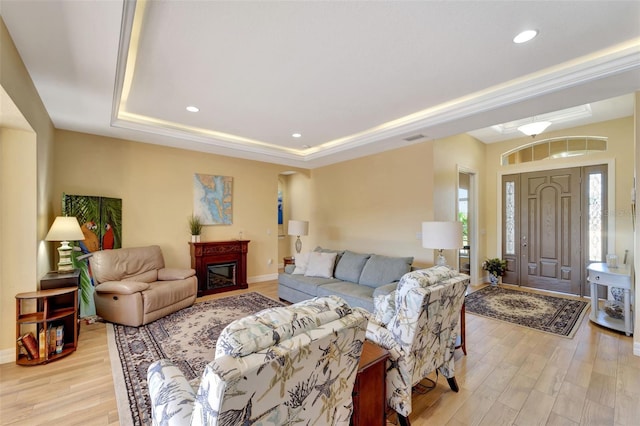 living room featuring a tray ceiling and light wood-type flooring