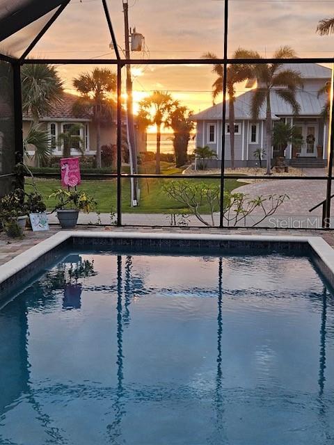 pool at dusk featuring glass enclosure