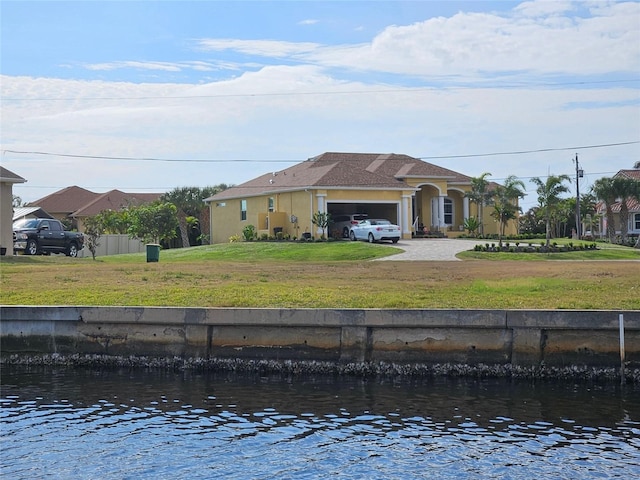 rear view of house with a yard, a water view, and a garage