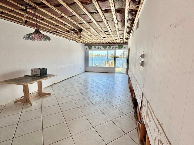 interior space with tile patterned flooring, wood walls, and a water view