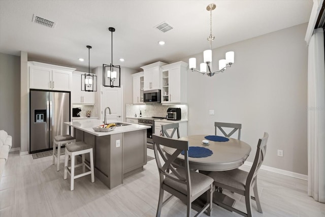 kitchen with decorative light fixtures, white cabinetry, sink, and appliances with stainless steel finishes