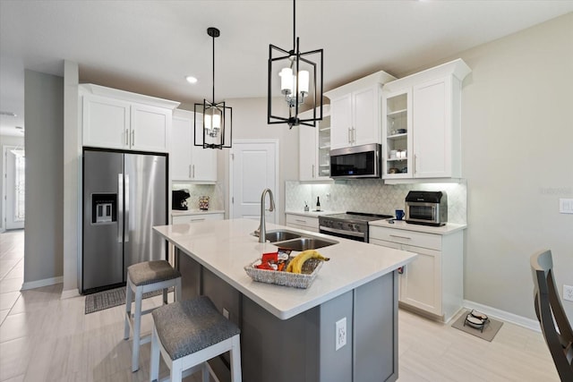 kitchen with white cabinetry, sink, backsplash, a kitchen island with sink, and appliances with stainless steel finishes