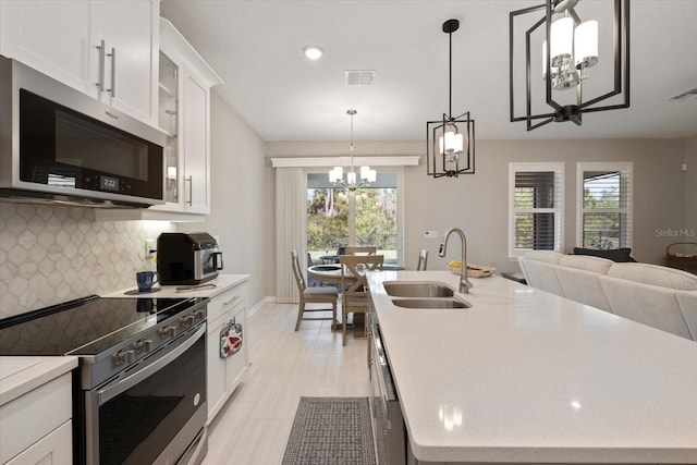 kitchen with a healthy amount of sunlight, white cabinetry, an island with sink, and appliances with stainless steel finishes