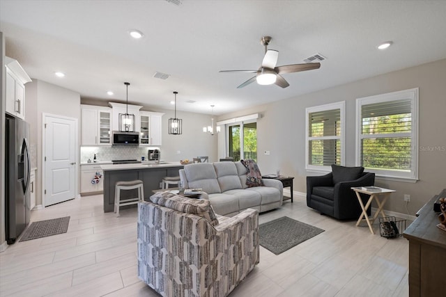 living room featuring ceiling fan with notable chandelier