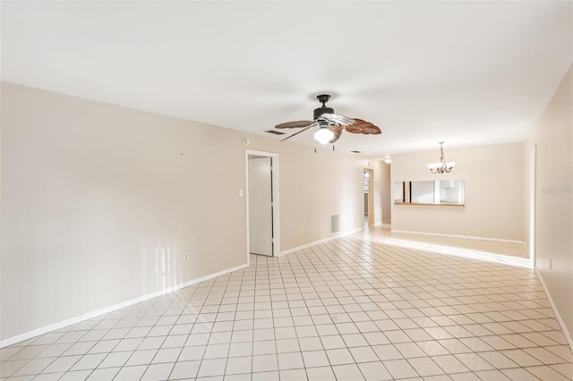 tiled spare room featuring ceiling fan with notable chandelier