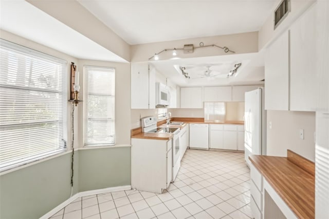 kitchen with white appliances, sink, ceiling fan, light tile patterned floors, and white cabinetry