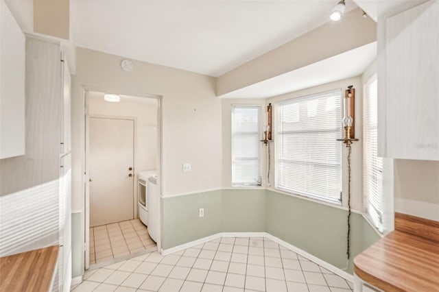 unfurnished dining area featuring light tile patterned flooring and washer / dryer