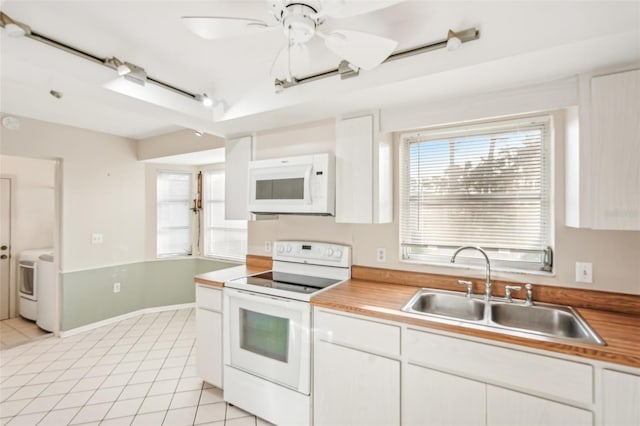 kitchen featuring white appliances, sink, light tile patterned flooring, white cabinetry, and washer / clothes dryer