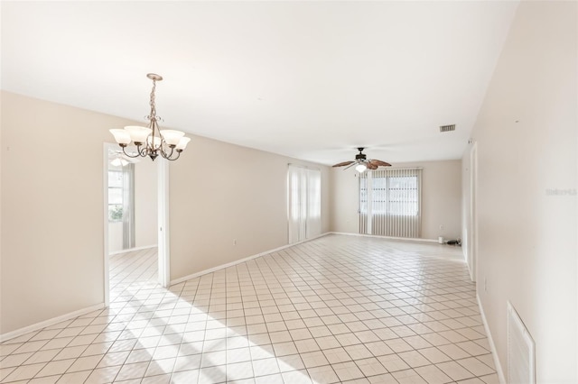 tiled empty room with plenty of natural light and ceiling fan with notable chandelier