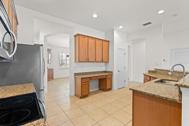 kitchen featuring light stone countertops, sink, light tile patterned flooring, and stainless steel appliances