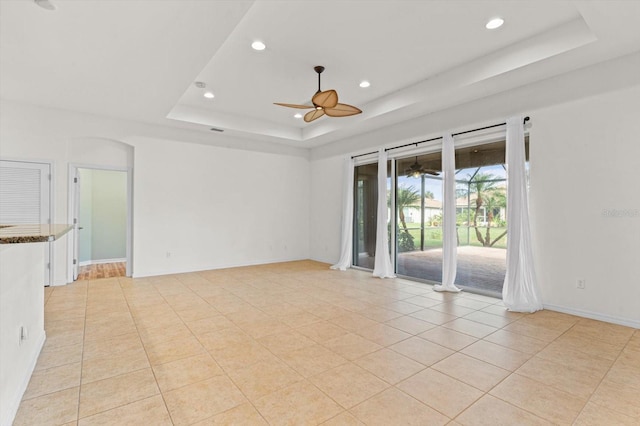 tiled spare room featuring a tray ceiling and ceiling fan