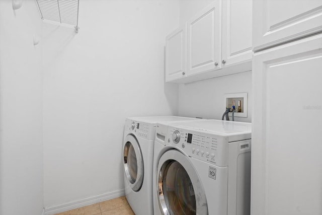 laundry area with light tile patterned floors, cabinets, and independent washer and dryer