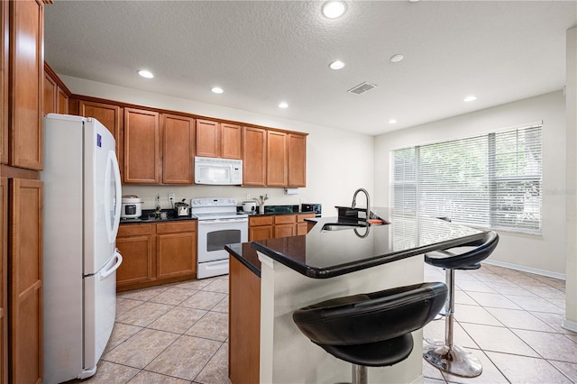 kitchen featuring white appliances, a center island with sink, a breakfast bar area, and sink