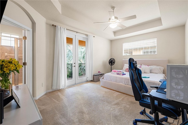 carpeted bedroom with access to exterior, french doors, a textured ceiling, a tray ceiling, and ceiling fan