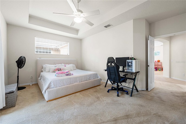 carpeted bedroom featuring a raised ceiling and ceiling fan