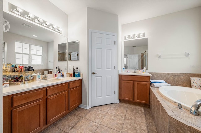 bathroom featuring tile patterned flooring, vanity, and a relaxing tiled tub