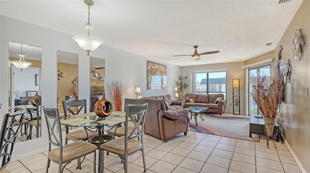 tiled dining space with ceiling fan and a textured ceiling