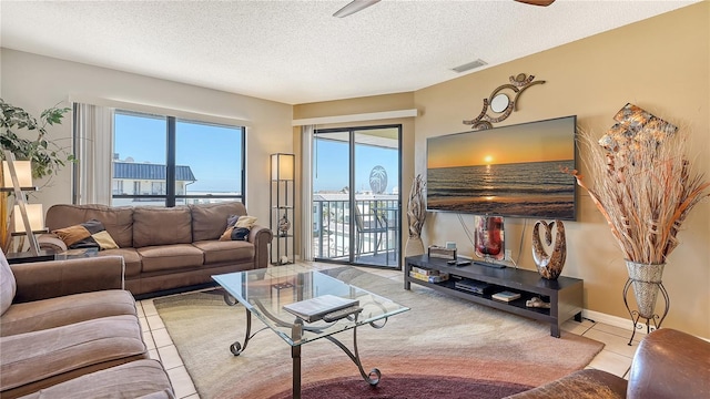 living room featuring ceiling fan, light tile patterned flooring, and a textured ceiling