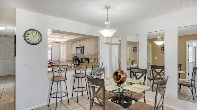 dining space featuring light tile patterned floors, a healthy amount of sunlight, and a textured ceiling