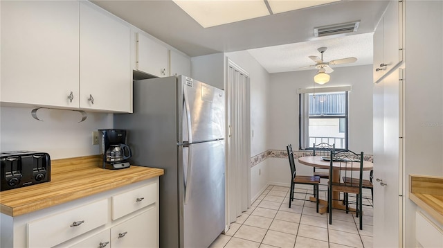 kitchen with white cabinets, ceiling fan, light tile patterned floors, and stainless steel refrigerator