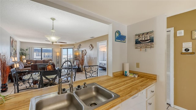 kitchen featuring a textured ceiling, ceiling fan, sink, light tile patterned floors, and hanging light fixtures