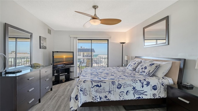 bedroom featuring access to outside, ceiling fan, light hardwood / wood-style flooring, and a textured ceiling