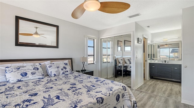 bedroom with ceiling fan, light wood-type flooring, and a textured ceiling