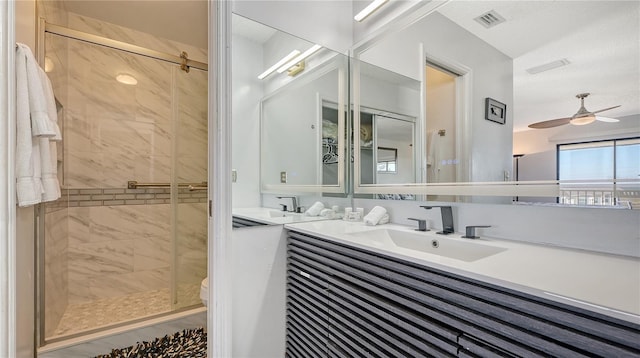 bathroom featuring vanity, toilet, a shower with door, and ceiling fan