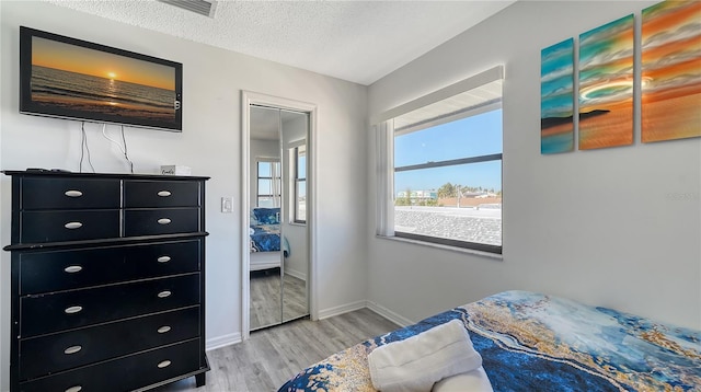 bedroom with a textured ceiling and light hardwood / wood-style floors