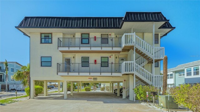 view of building exterior with a carport, concrete driveway, and stairway