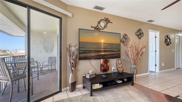 tiled living area featuring baseboards, visible vents, and a textured ceiling