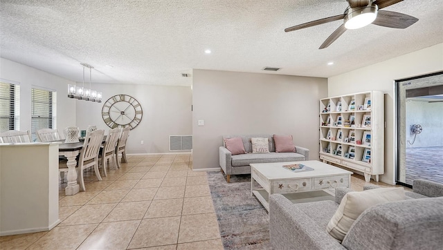 living room with light tile patterned floors, ceiling fan with notable chandelier, and a textured ceiling