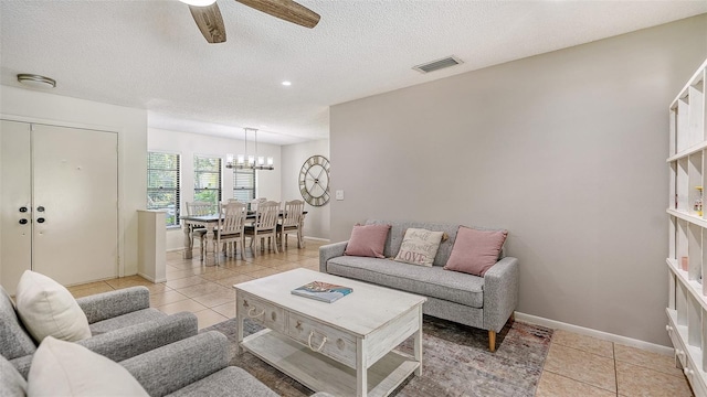 tiled living room featuring ceiling fan with notable chandelier and a textured ceiling