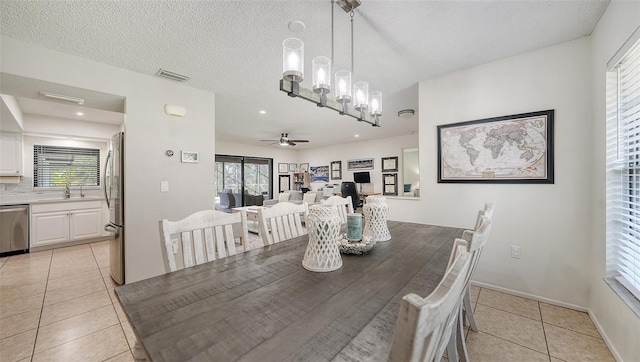 tiled dining area with a textured ceiling, ceiling fan with notable chandelier, and sink