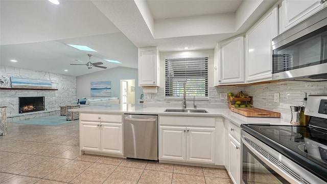 kitchen featuring white cabinets, sink, vaulted ceiling with skylight, and stainless steel appliances