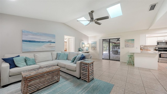 tiled living room featuring lofted ceiling with skylight and ceiling fan