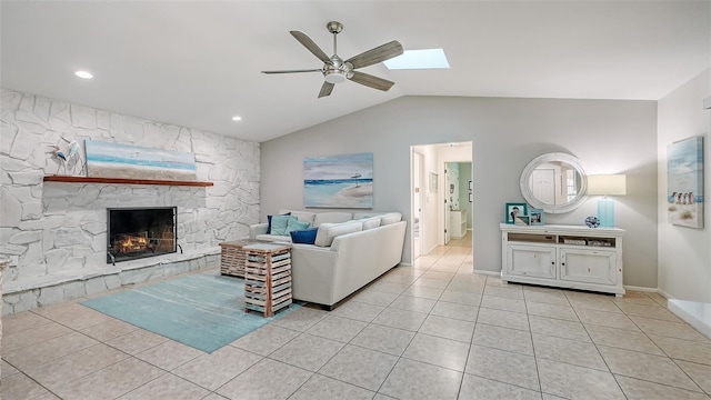 living room featuring a stone fireplace, ceiling fan, light tile patterned floors, and lofted ceiling