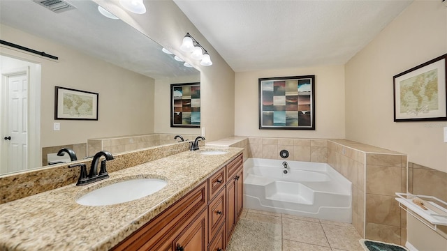 bathroom with a bathing tub, vanity, tile patterned floors, and a textured ceiling