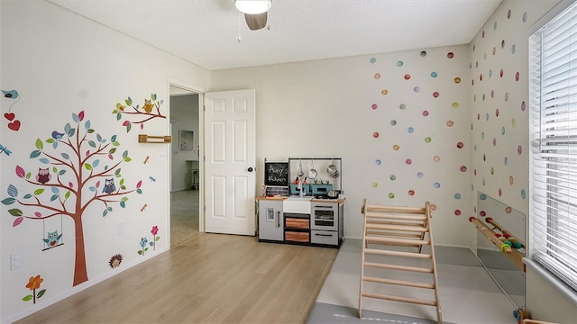 interior space featuring ceiling fan, light hardwood / wood-style flooring, and a textured ceiling