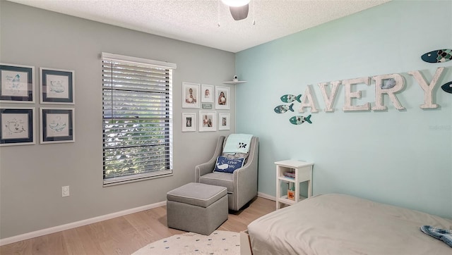 bedroom with ceiling fan, light hardwood / wood-style floors, and a textured ceiling