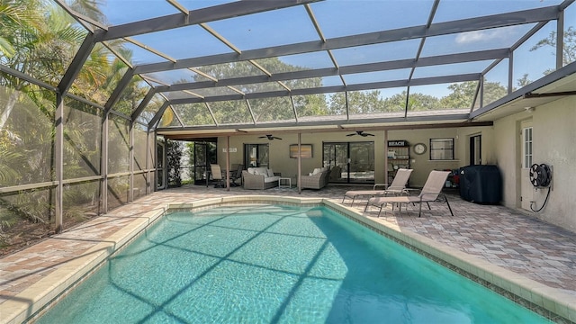 view of pool with an outdoor living space, ceiling fan, a patio area, and glass enclosure