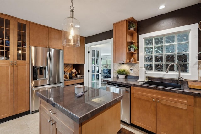 kitchen featuring sink, stainless steel appliances, pendant lighting, decorative backsplash, and a kitchen island