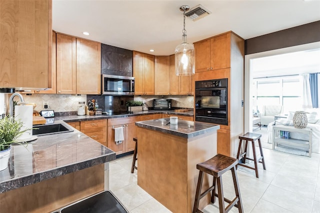 kitchen with a breakfast bar, a center island, oven, tasteful backsplash, and decorative light fixtures