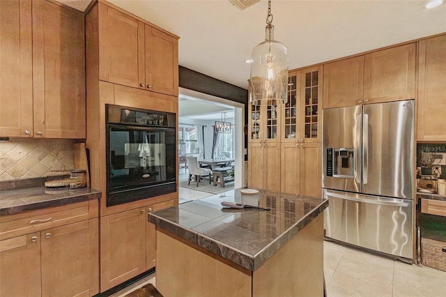 kitchen featuring a kitchen island, tasteful backsplash, stainless steel refrigerator with ice dispenser, black oven, and light tile patterned floors