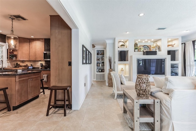 living room featuring built in shelves, a textured ceiling, and light tile patterned flooring