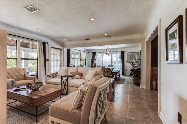 tiled living room featuring a chandelier and a textured ceiling