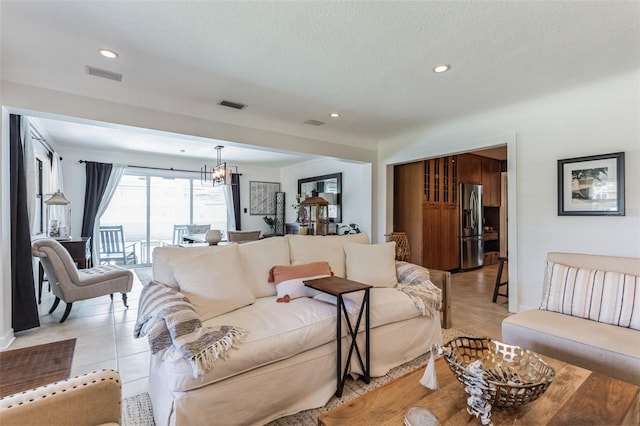 tiled living room featuring a textured ceiling and a notable chandelier